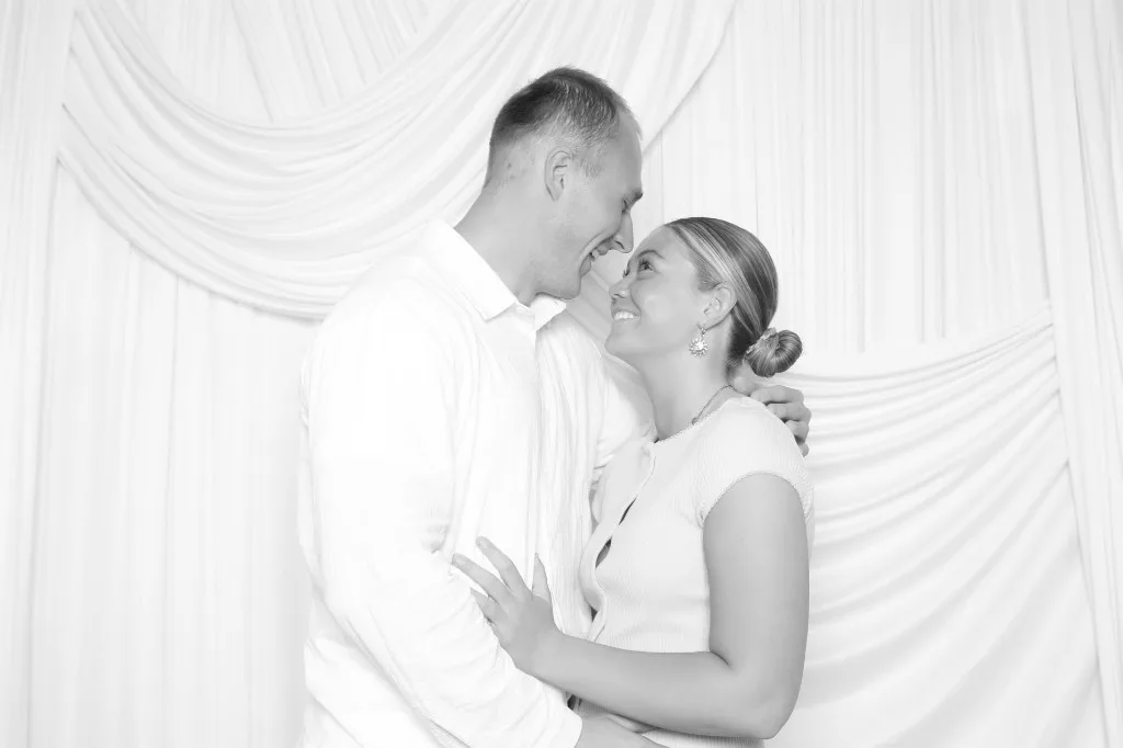 Couple embracing and smiling in a black and white photo booth portrait